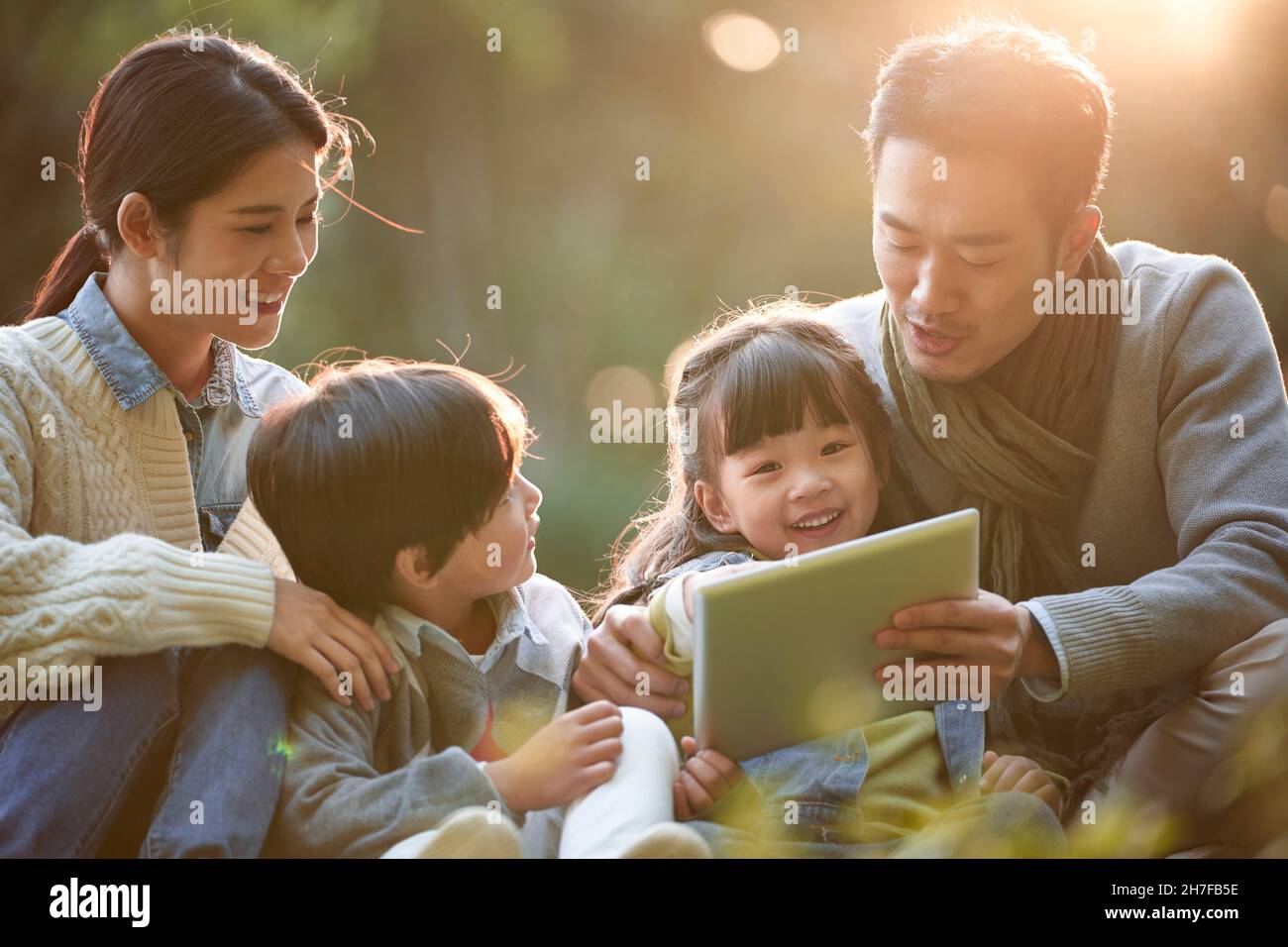 famiglia asiatica con due bambini che si rilassa all'aperto nel parco cittadino Foto Stock