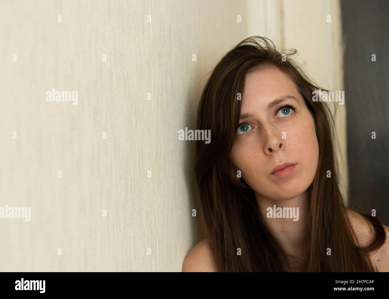 ritratto di una ragazza con capelli lunghi, con un aspetto triste. Una giovane ragazza è depressa, spazio copia. Disturbo della salute mentale. Sguardo pensivo in su Foto Stock