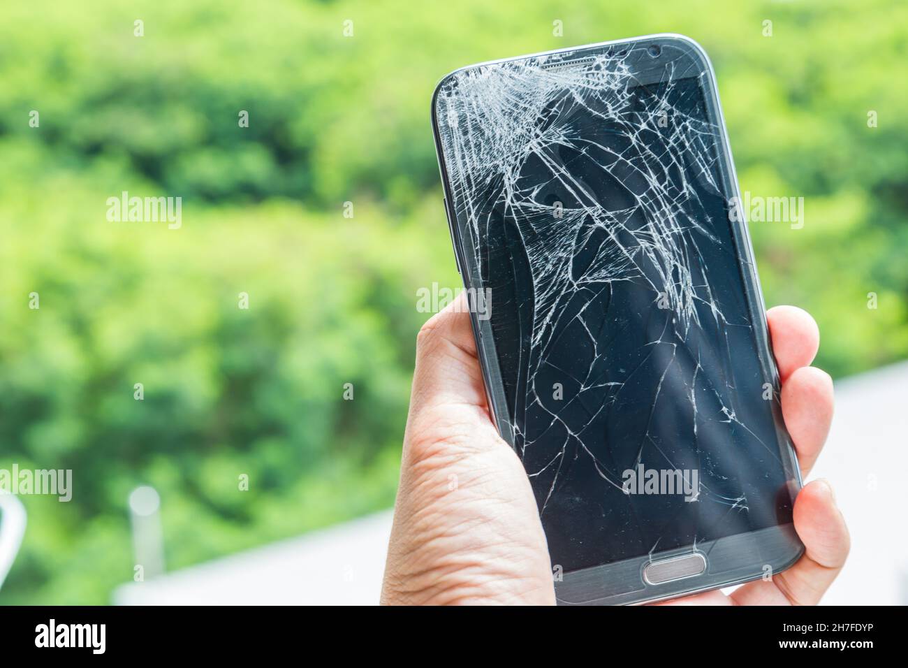 Lo smartphone cade a terra e lo schermo si danneggia con lo sfondo verde  bokeh Foto stock - Alamy