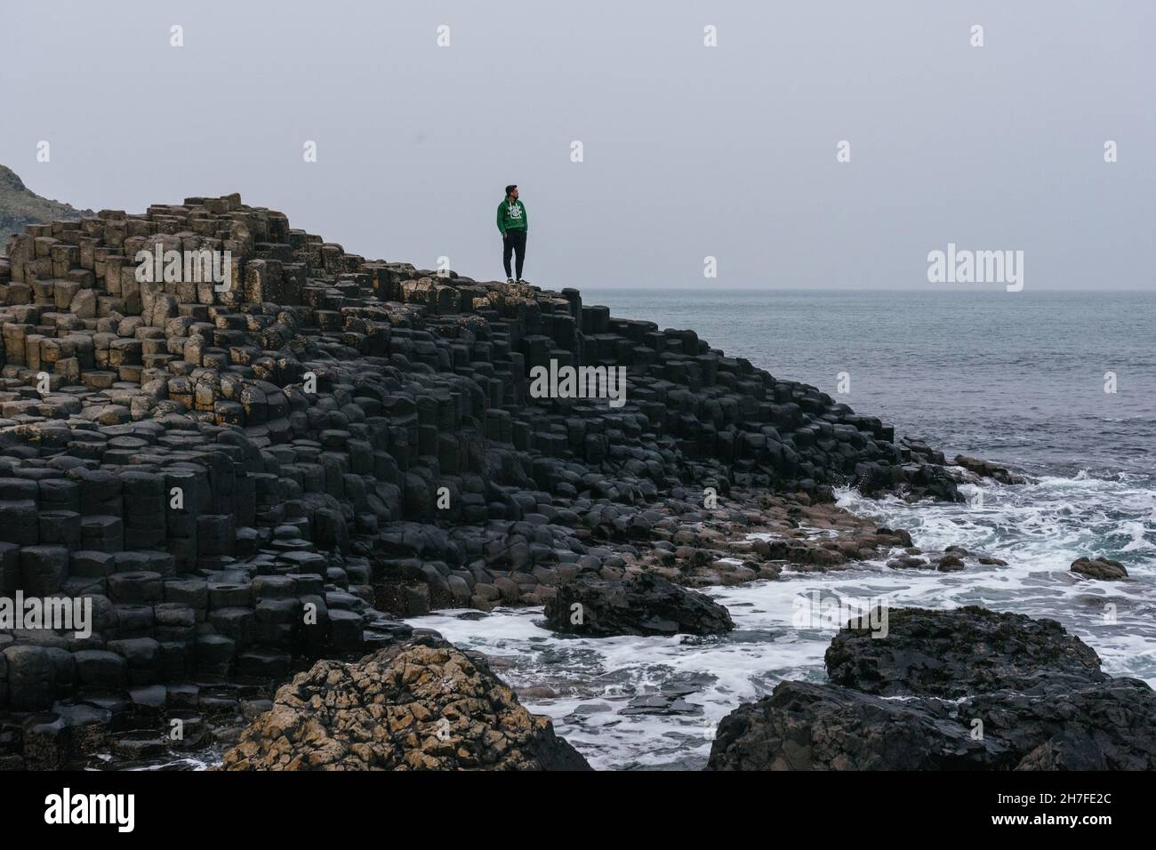 Cool spagnolo uomo in piedi su blocchi di cemento in Giant's Causeway a Bushmills, Regno Unito Foto Stock