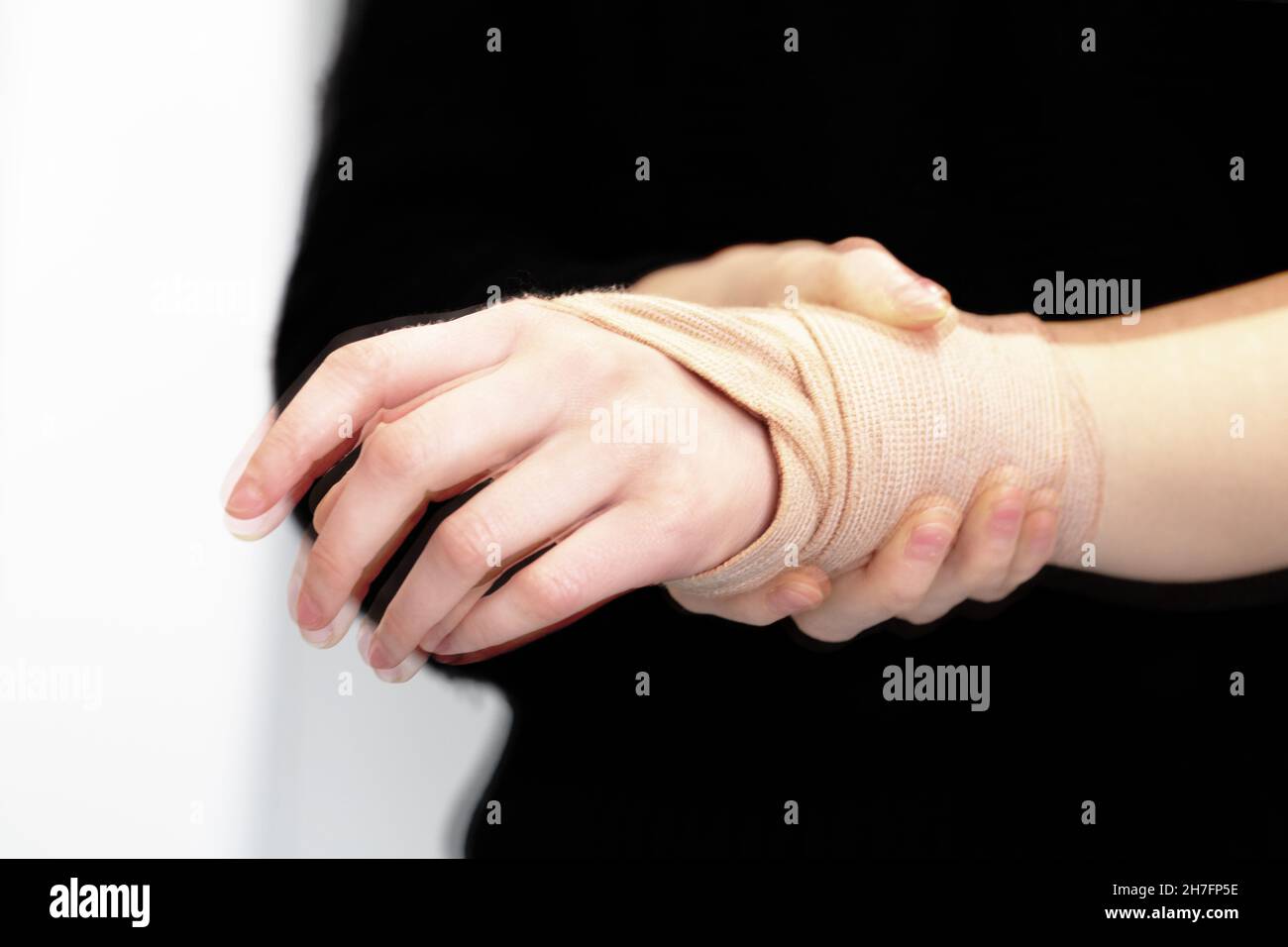 Donna che afferra un polso, sequestrata con tremori a causa del morbo di Parkinson Foto Stock