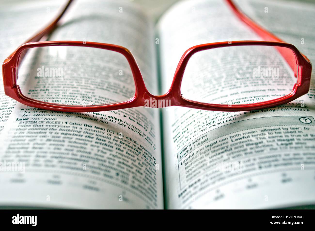Gli occhiali da lettura rossi si trovano sul dizionario inglese Foto Stock