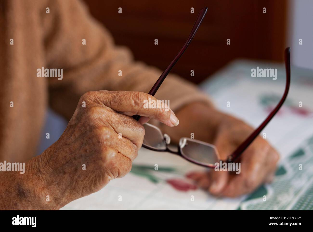 Un primo piano delle mani di una donna anziana che regge un paio di occhiali MR - Model rilasciato Foto Stock