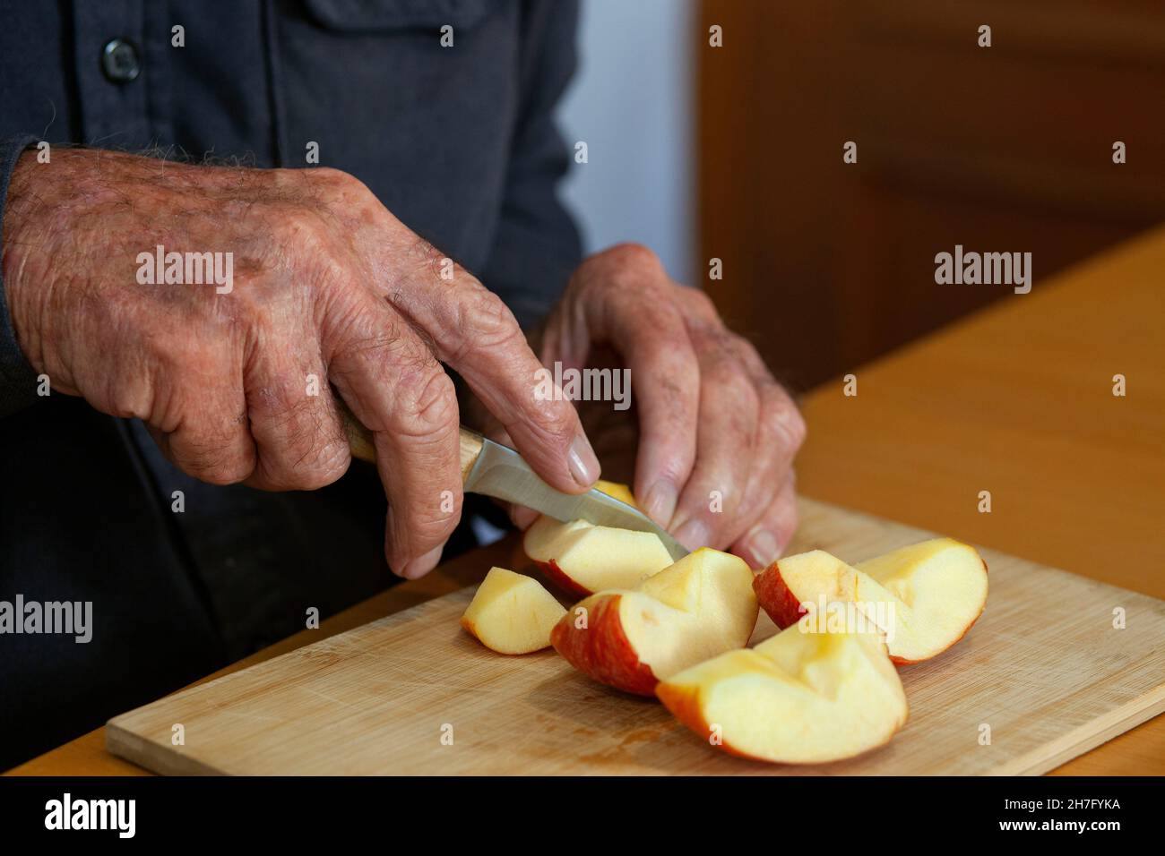 Un primo piano delle mani di un uomo anziano tagliando una mela MR - Model rilasciato Foto Stock