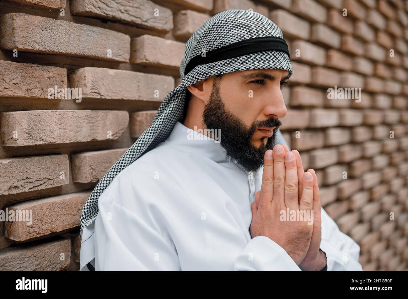 Giovane uomo arabo che prega e guarda concentrandosi Foto Stock