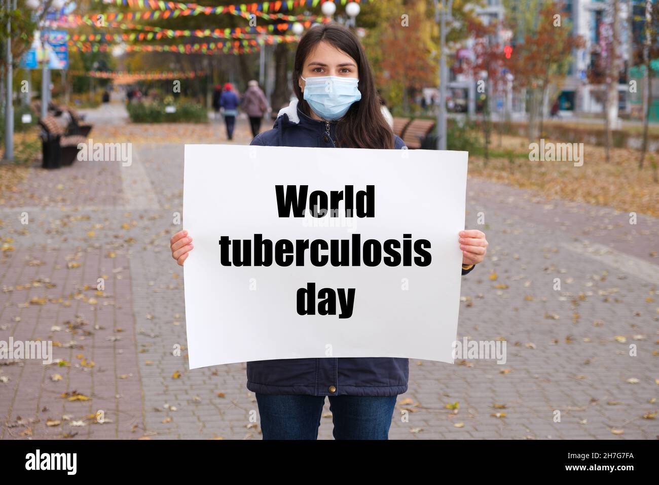 Una donna in una maschera medica contiene un poster con il testo Giornata Mondiale della tubercolosi Foto Stock