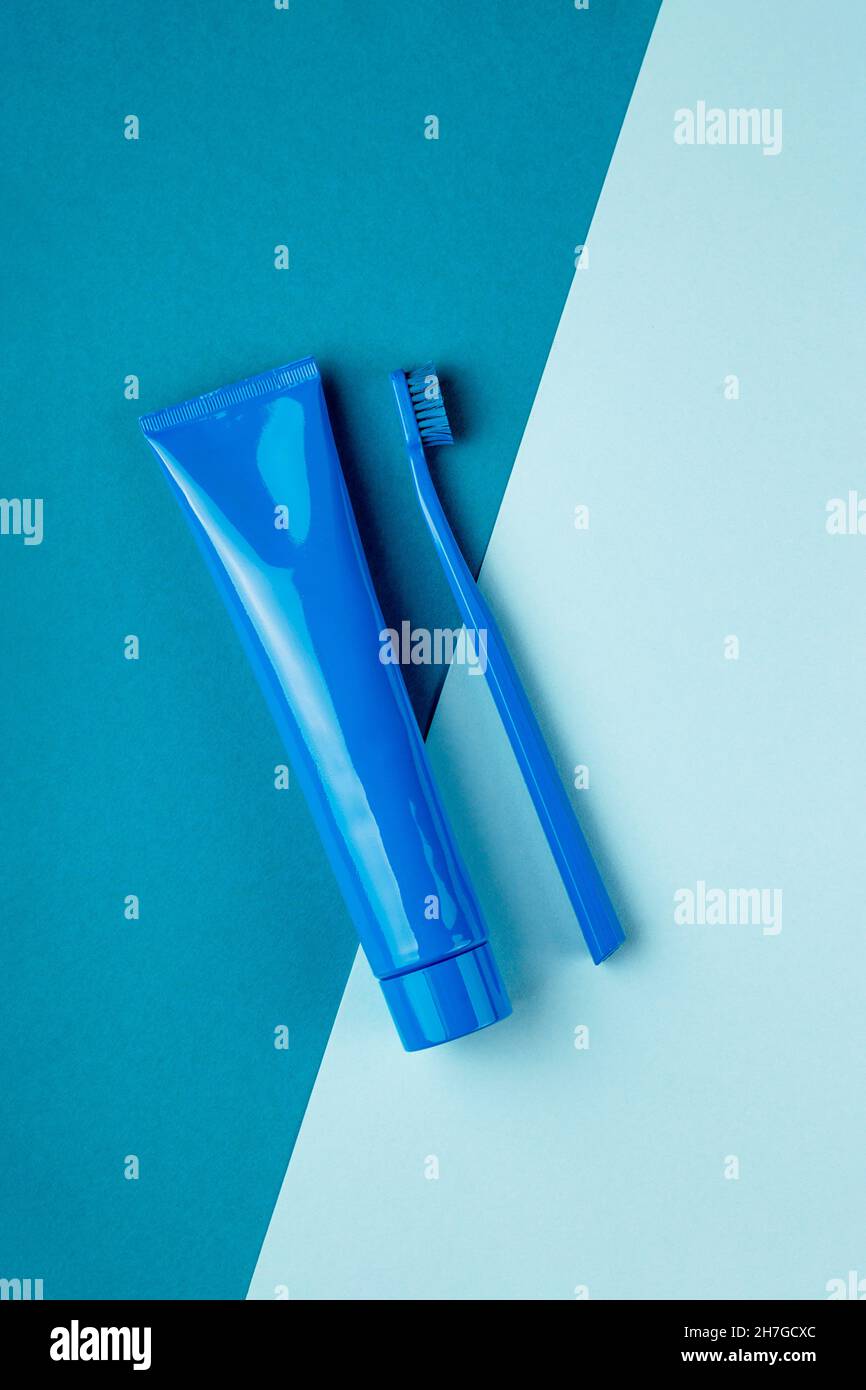Il tubo blu di dentifricio e lo spazzolino blu si trovano su uno sfondo blu combinato. Vista dall'alto Foto Stock