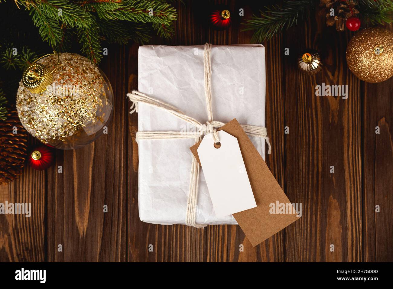 Regalo di Natale Tag mockup. Confezione regalo minimale bianca su tavolo in legno con decorazioni natalizie. Foto Stock