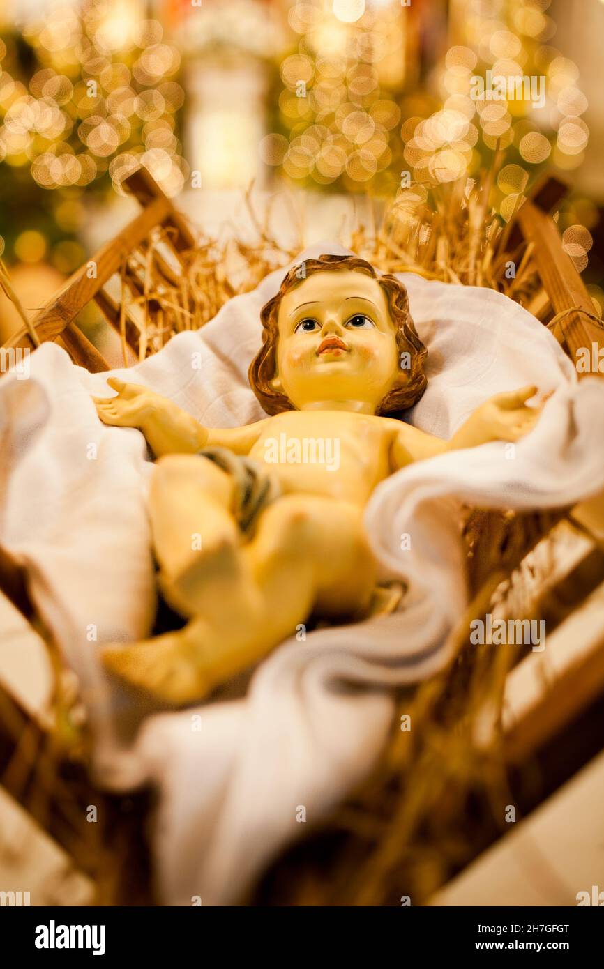 Gesù Bambino nella mangiatoia, luce di Natale sugli alberi sullo sfondo, fotografia artistica, foto sull'albero di natale che guarda nella chiesa Foto Stock