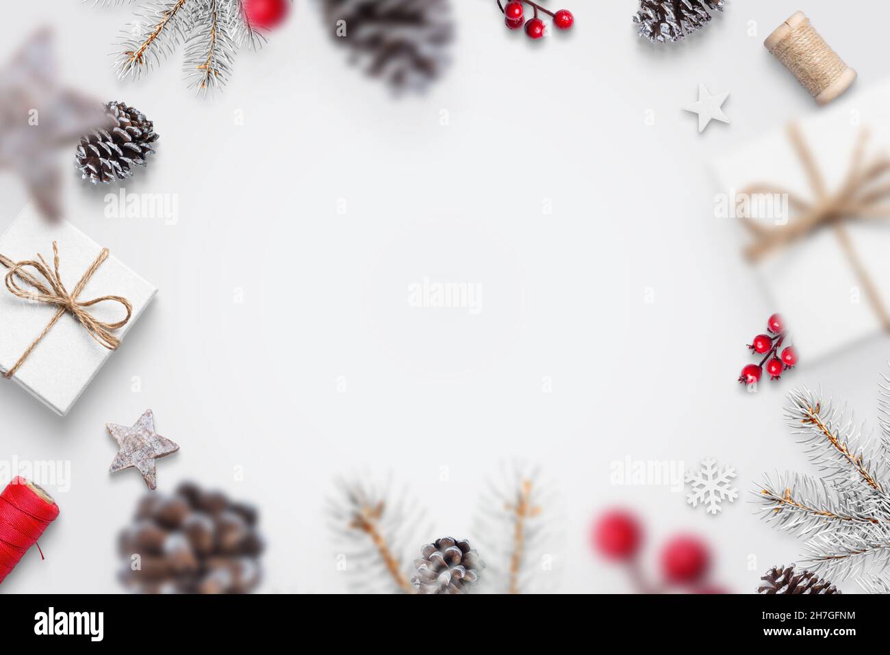 Le decorazioni di Natale cadono sul concetto del tavolo bianco. Regali, pino, coni, bacche rosse, rami di albero, fiocchi di neve. Vista dall'alto, piatto, biglietto d'auguri c Foto Stock