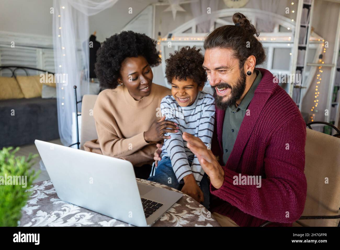 Giovane famiglia allegra multietnica che parla con i parenti in video chat Foto Stock