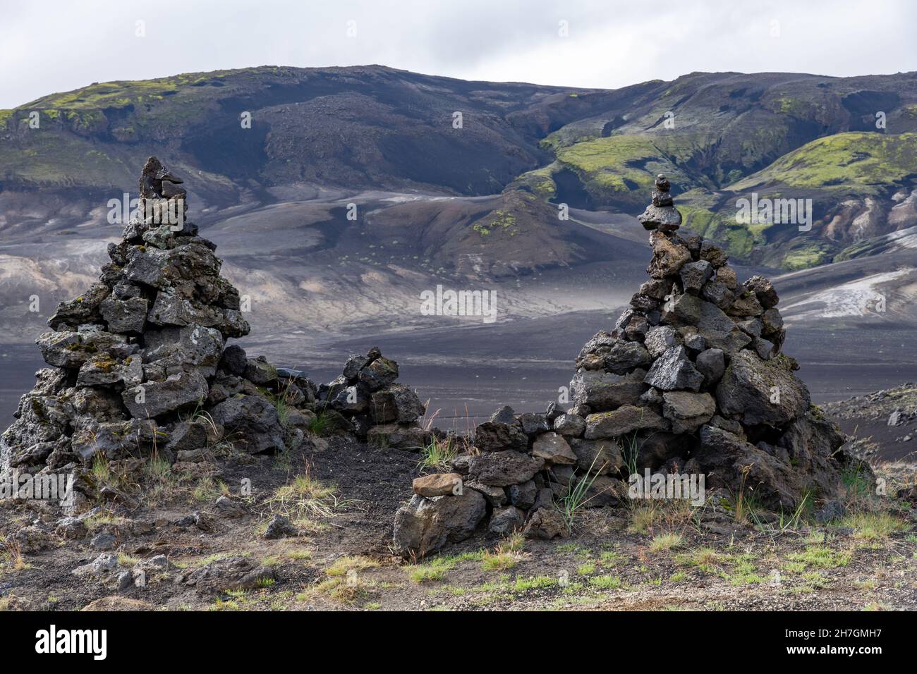 Vista ad angolo basso di alcune pile di roccia lavica o cairns di roccia lavica in un paesaggio altrimenti arido di deserto lavico vicino al vulcano Katla in Islanda Foto Stock