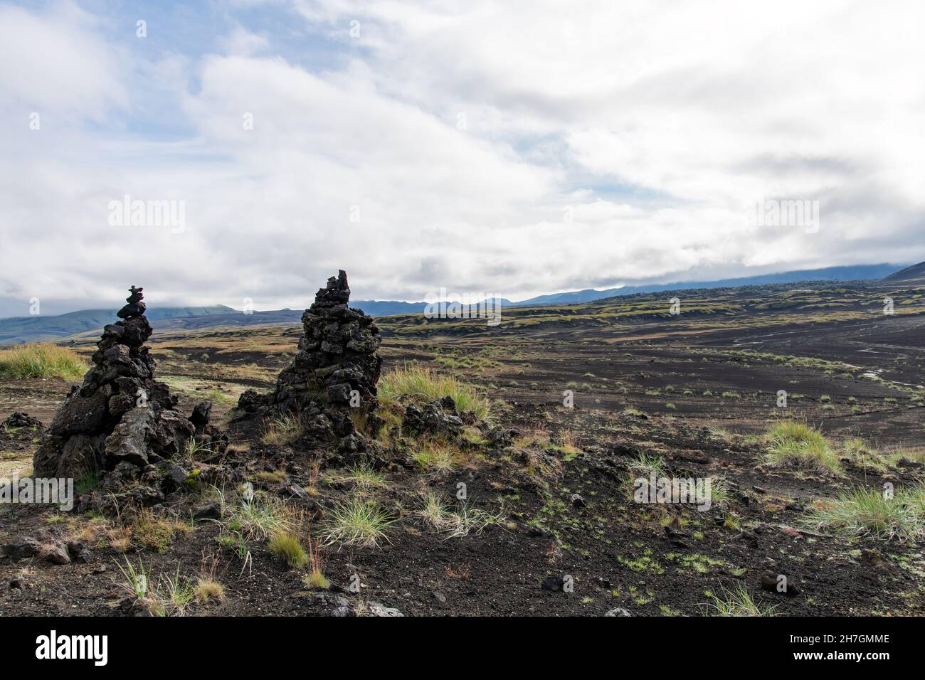 Vista ad angolo basso di alcune pile di roccia lavica o cairns di roccia lavica in un paesaggio altrimenti arido di deserto lavico vicino al vulcano Katla in Islanda Foto Stock