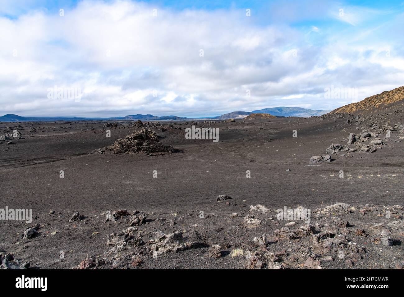 Vista ad angolo basso del paesaggio arido di roccia lavica nera dal vicino vulcano Katla sull'Islanda con montagne sullo sfondo Foto Stock