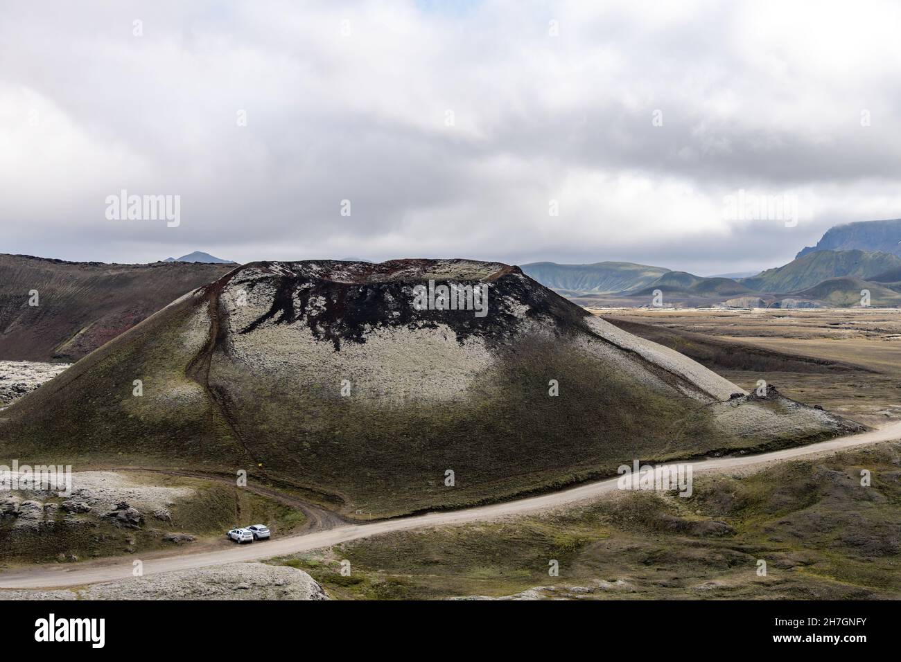 Alto angolo di vista di un vulcano dormiente sull'altopiano vulcanico vicino al vulcano Katla in Islanda con montagne sullo sfondo e auto parcheggiate Foto Stock