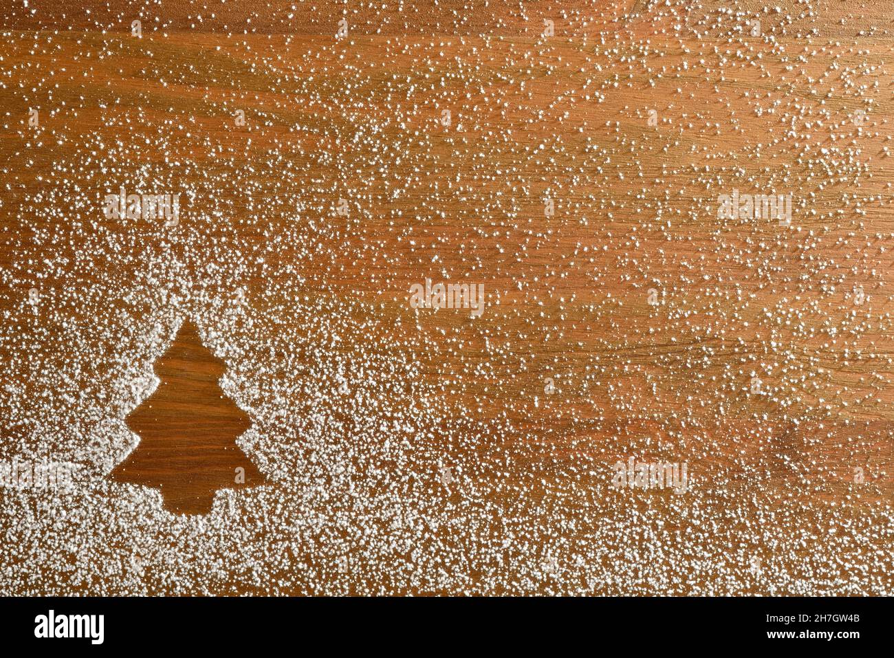 Sfondo natalizio con disegno a forma di abete con polvere di zucchero a velo su base di legno. Vista dall'alto. Composizione orizzontale. Foto Stock