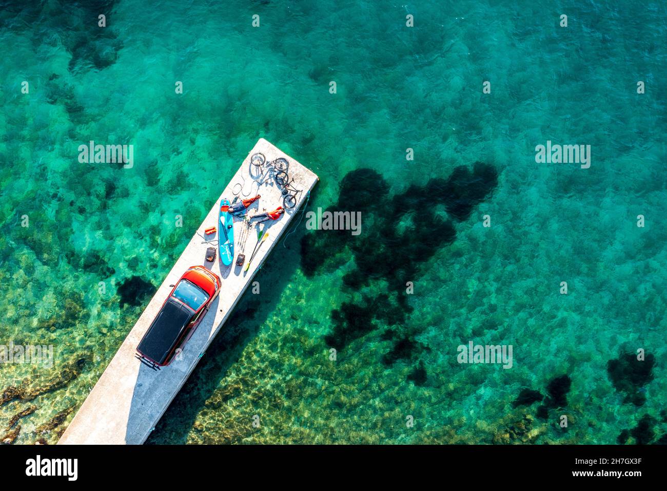 Viaggio in Croazia, due persone con attrezzature per il tempo libero, biciclette, SUP board e camper su un molo Foto Stock