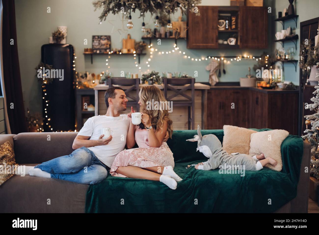 Marito, moglie e bambino si rilassano sul divano la mattina di Natale Foto Stock