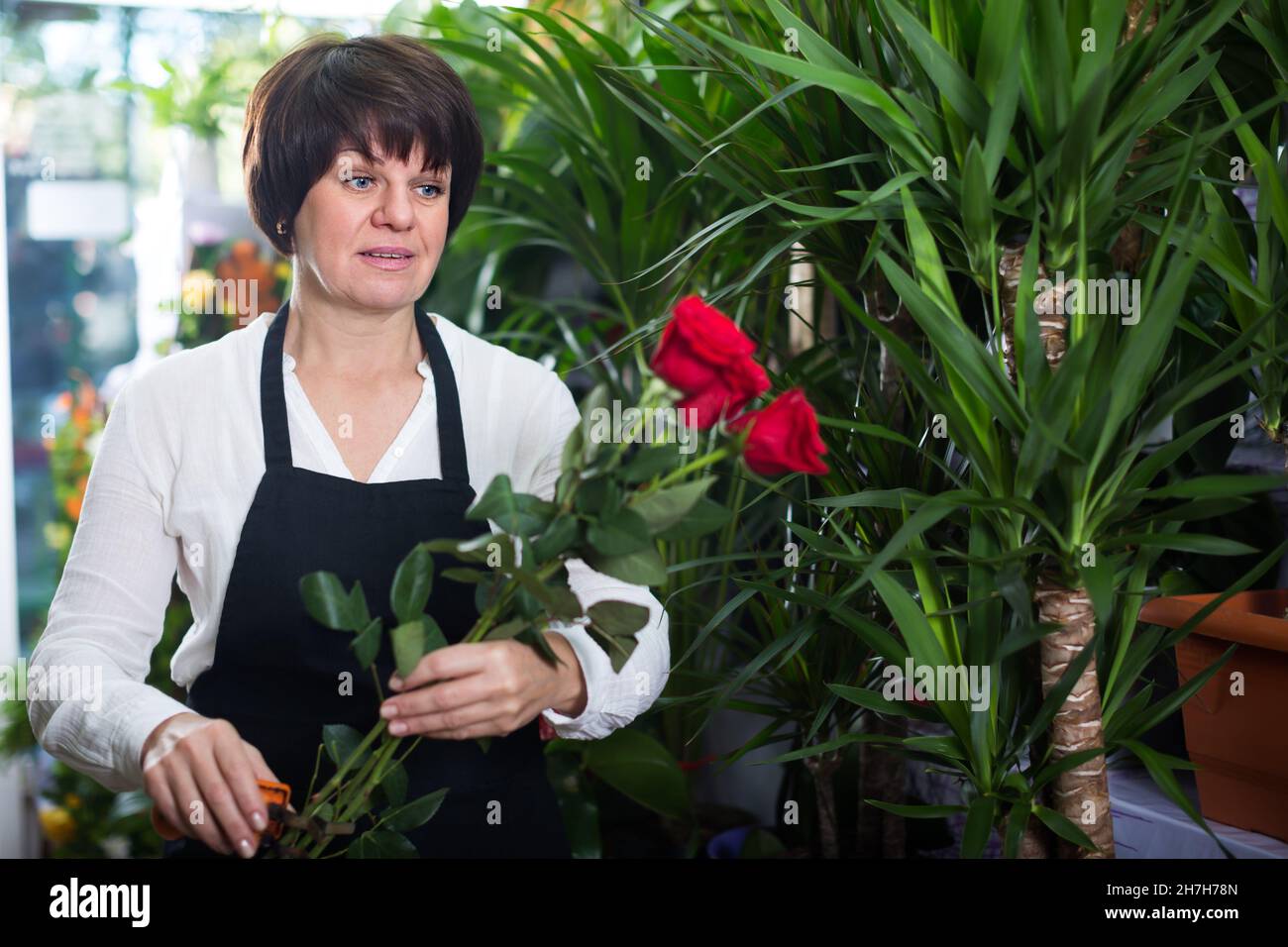 Assistente di negozio felice che mostra rose rosse luminose Foto Stock