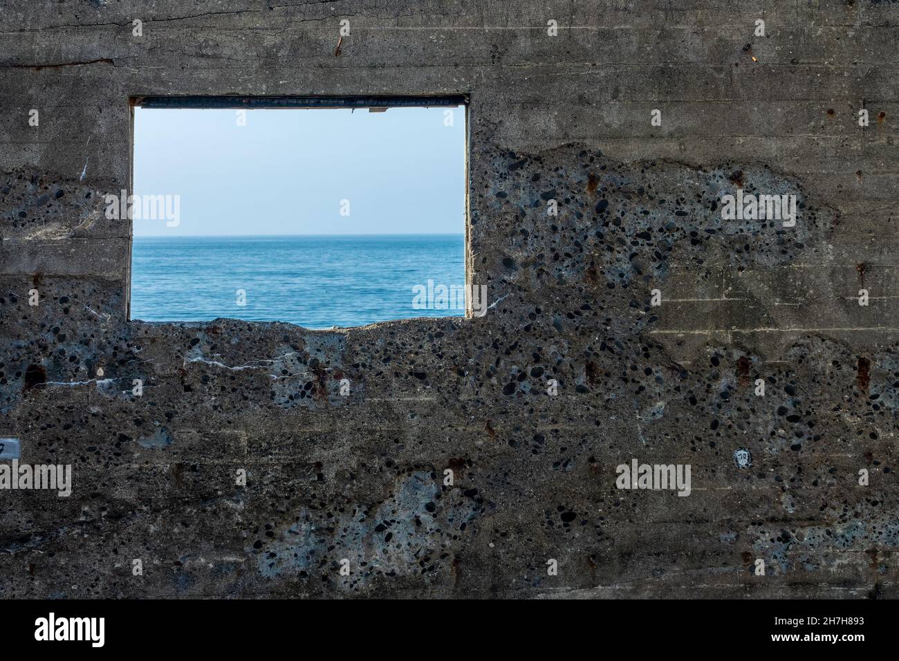 L'oceano e il cielo blu visto attraverso un buco in un muro di cemento Foto Stock