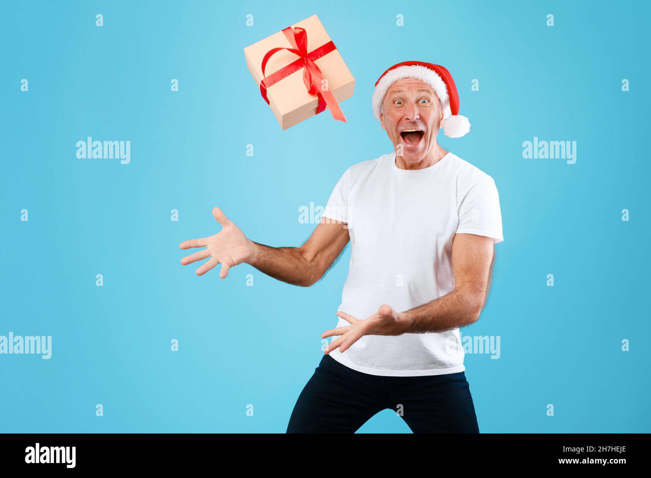 L'uomo maturo che lancia il regalo di Natale in su a Studio Foto Stock