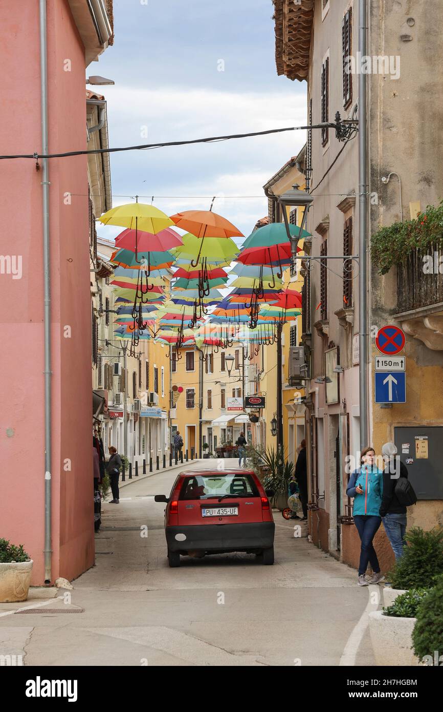 Ombrelloni aperti appesi a archi nella strada di Novigrad, Istria, Croazia, Europa. Foto Stock