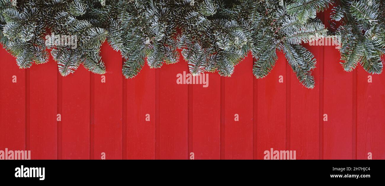 banner o immagine di intestazione della decorazione natalizia con legno rosso e rami di abete verde Foto Stock