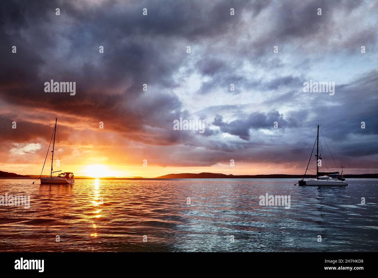 Ora d'oro al tramonto a Nelson Bay, New South Wales Australia, mentre una tempesta si sposta con le barche ormeggiate sull'acqua. Foto Stock