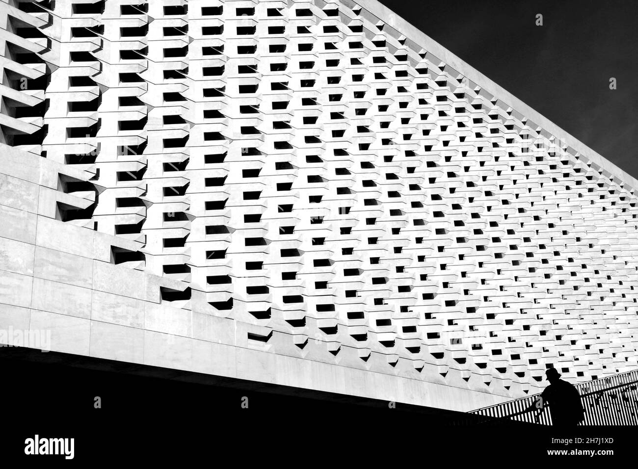 Immagine in scala di grigi di una facciata moderna dell'edificio e di una silhouette personale nell'angolo Foto Stock