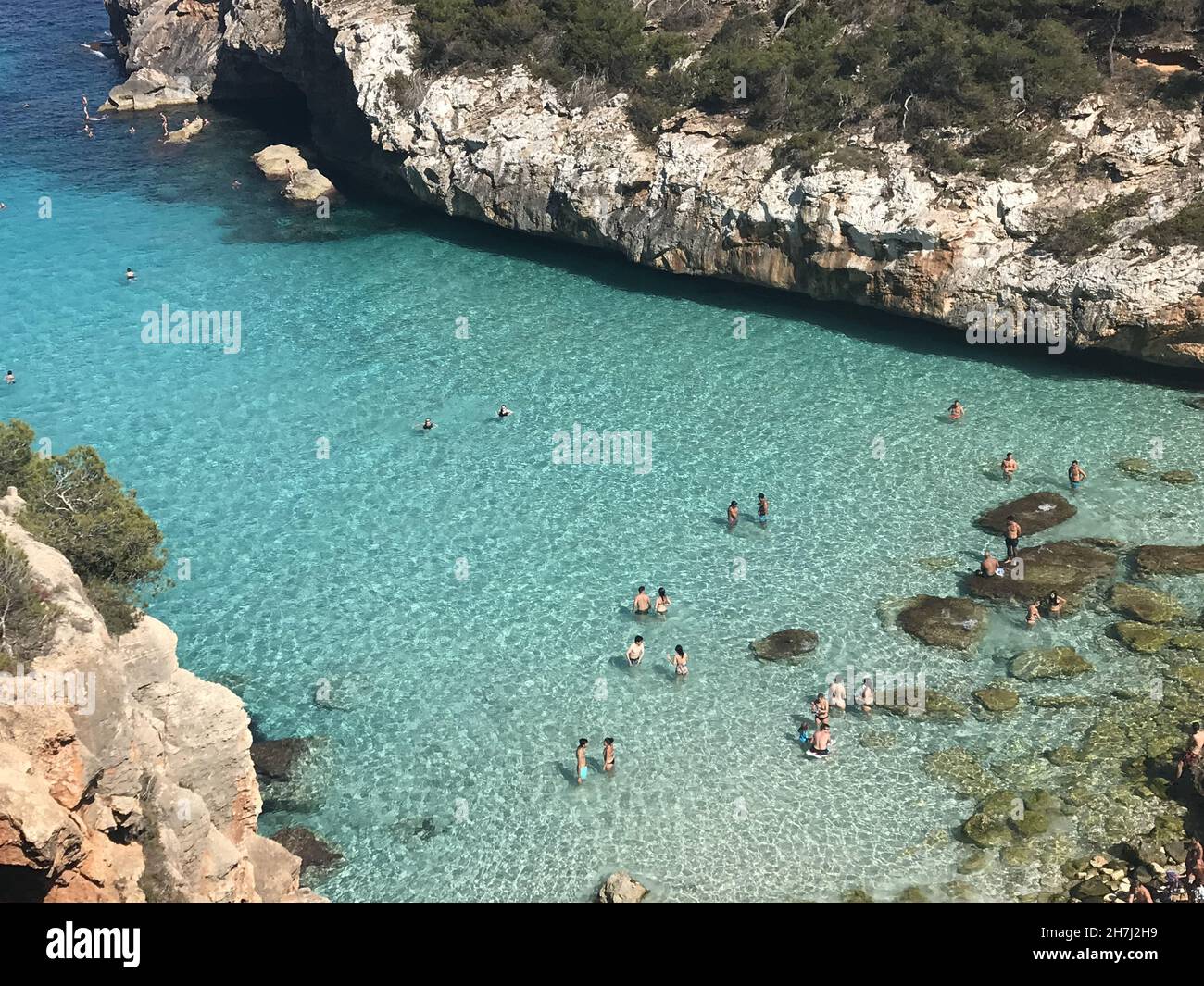 Alto angolo di persone che nuotano nelle acque turchesi del mare tra scogliere rocciose Foto Stock
