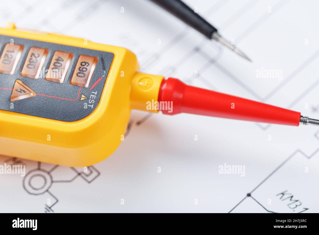 Indicatore di tensione giallo in primo piano sullo schema elettrico. Test e verifica delle reti elettriche Foto Stock