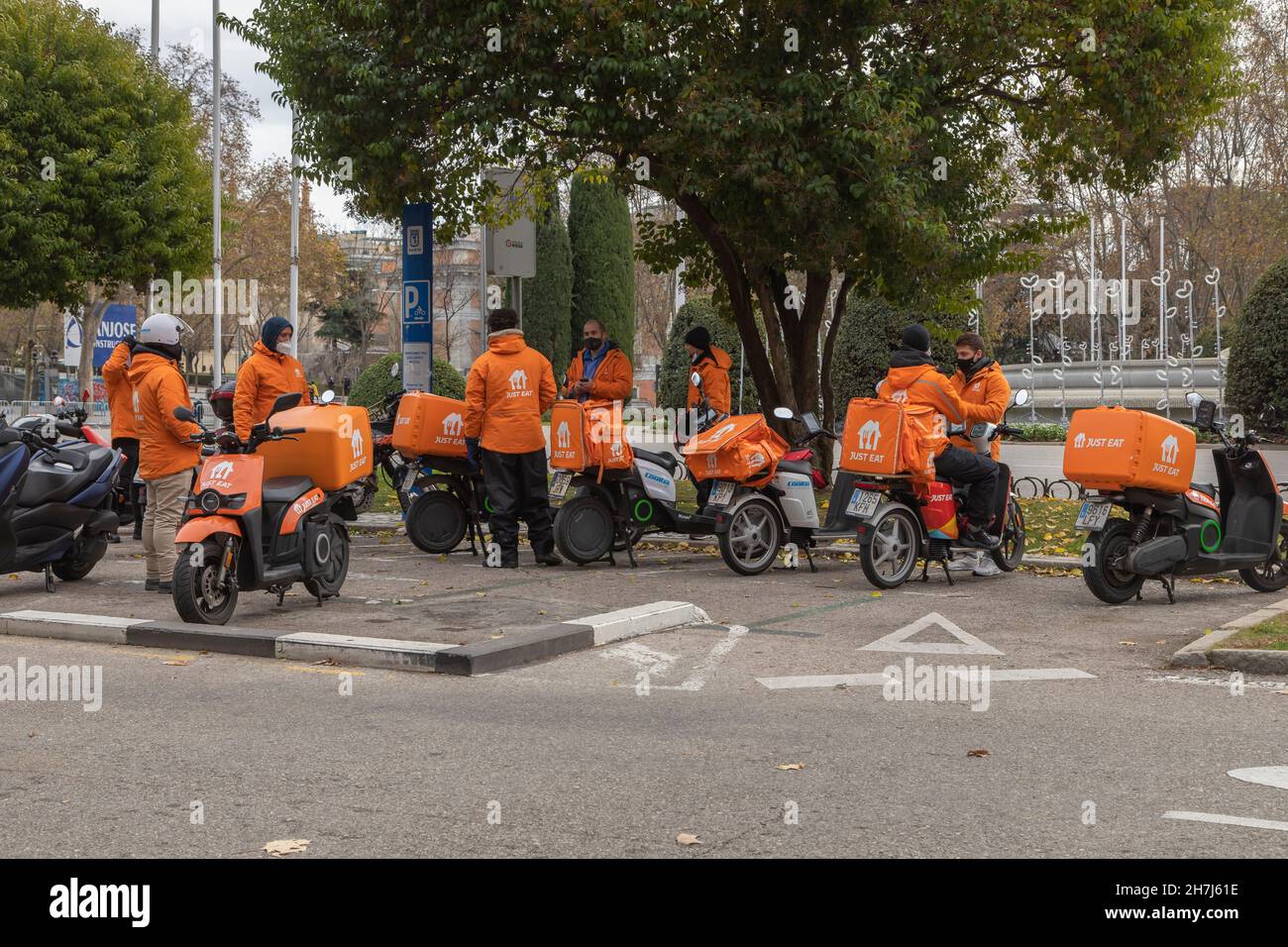 Madrid, Spagna - 27 dicembre 2020: Diversi piloti e addetti alla consegna di cibo, della compagnia Just Eat, si sono riuniti per una pausa, chiacchierando con il loro motociclista Foto Stock
