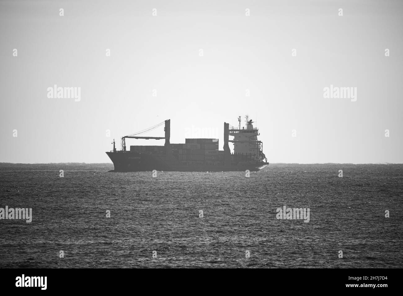 BARCELLONA, SPAGNA - 25 ottobre 2021: Una scala di grigi di una nave da carico all'orizzonte, Barcellona, Spagna Foto Stock