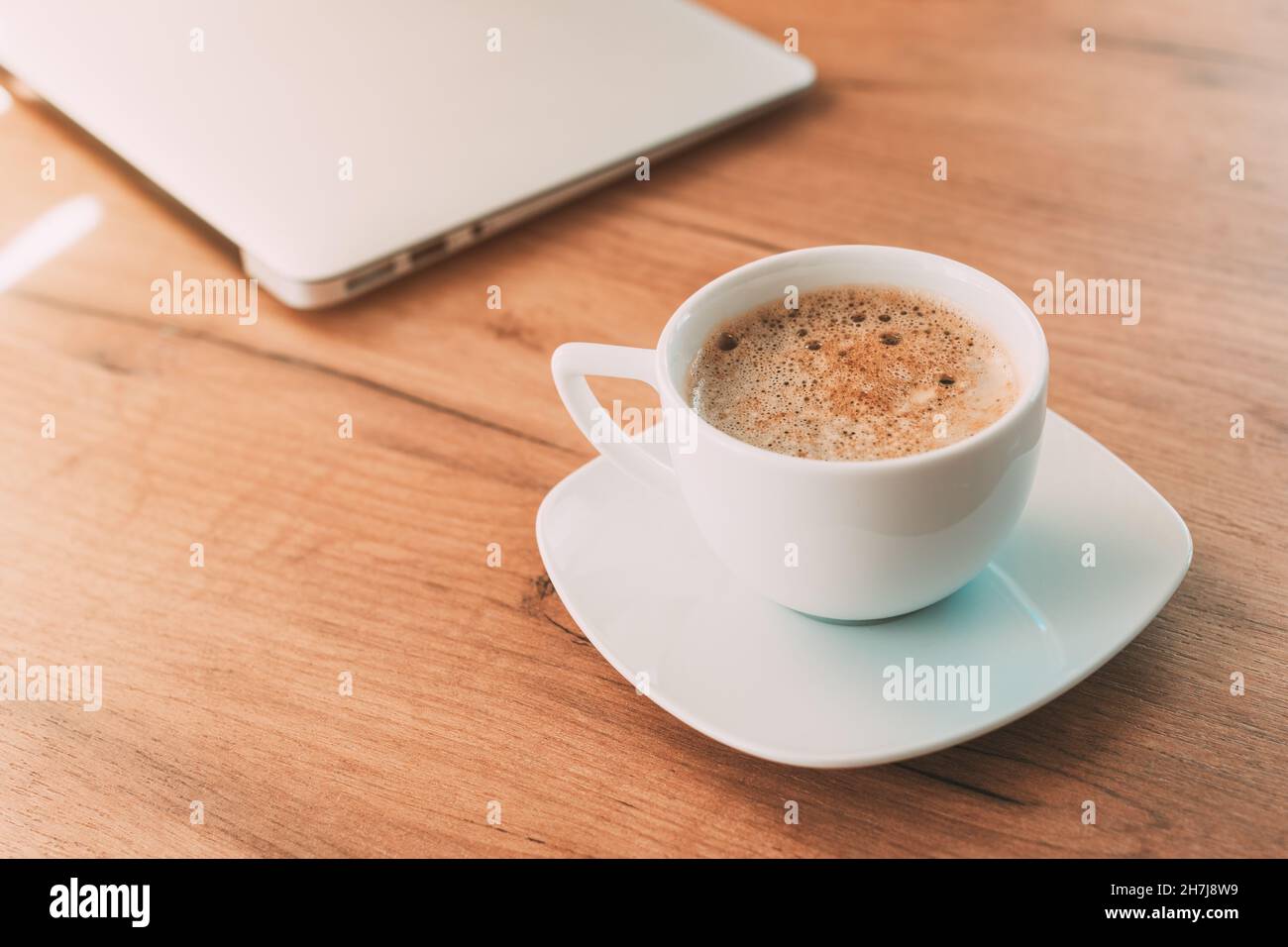 Bevi la tazza di caffè prima di iniziare a lavorare sul computer portatile, fuoco selettivo Foto Stock