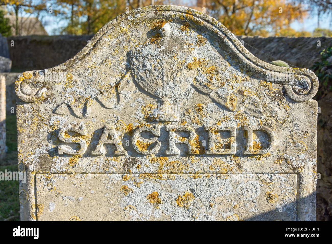 'Sacred' arruolato su un'antica pietra nel cimitero, la chiesa di San Pietro, Church Street, Yaxley, Cambridgeshire, Inghilterra, Regno Unito Foto Stock