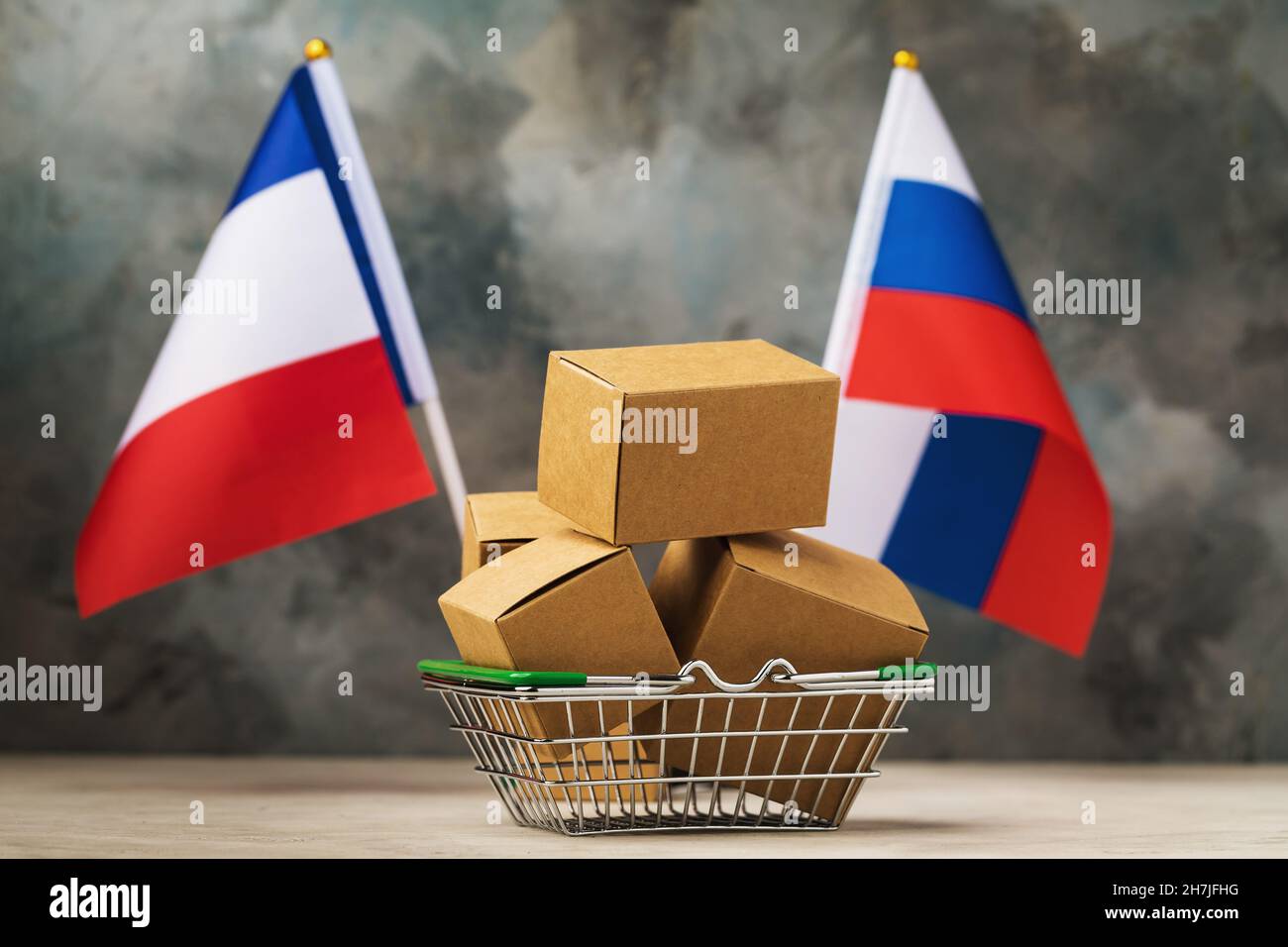 Vari scatoloni in un paniere alimentare e due bandiere su uno sfondo astratto, il concetto di commercio tra Francia e Russia Foto Stock