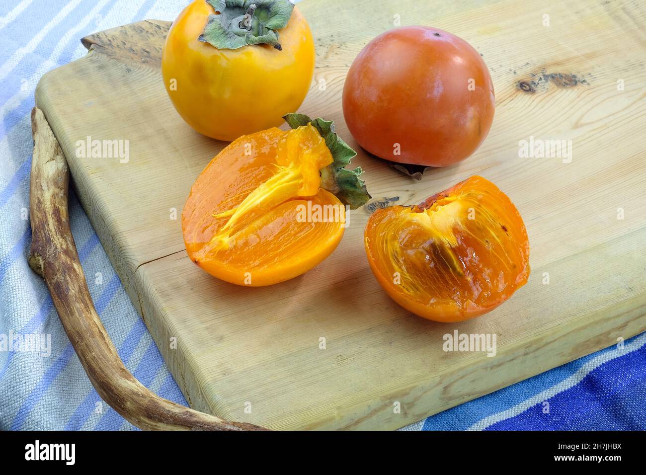 Persimmone fresco su un piano di legno. Persimmon di varietà diverse. Deliziosa frutta sana in autunno. Persimmon maturo, tagliato a metà. Foto Stock