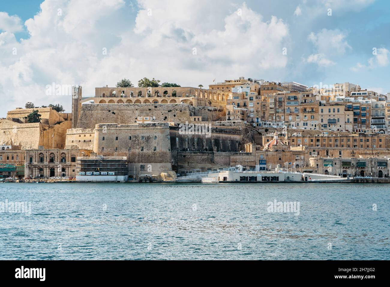 Vista panoramica della Valletta, Malta. Skyline della città dal porto di Birgu Vittoriosa. Paesaggio urbano tranquillo, giorno estivo soleggiato. Case sul lungomare e Upper Barrakka GA Foto Stock