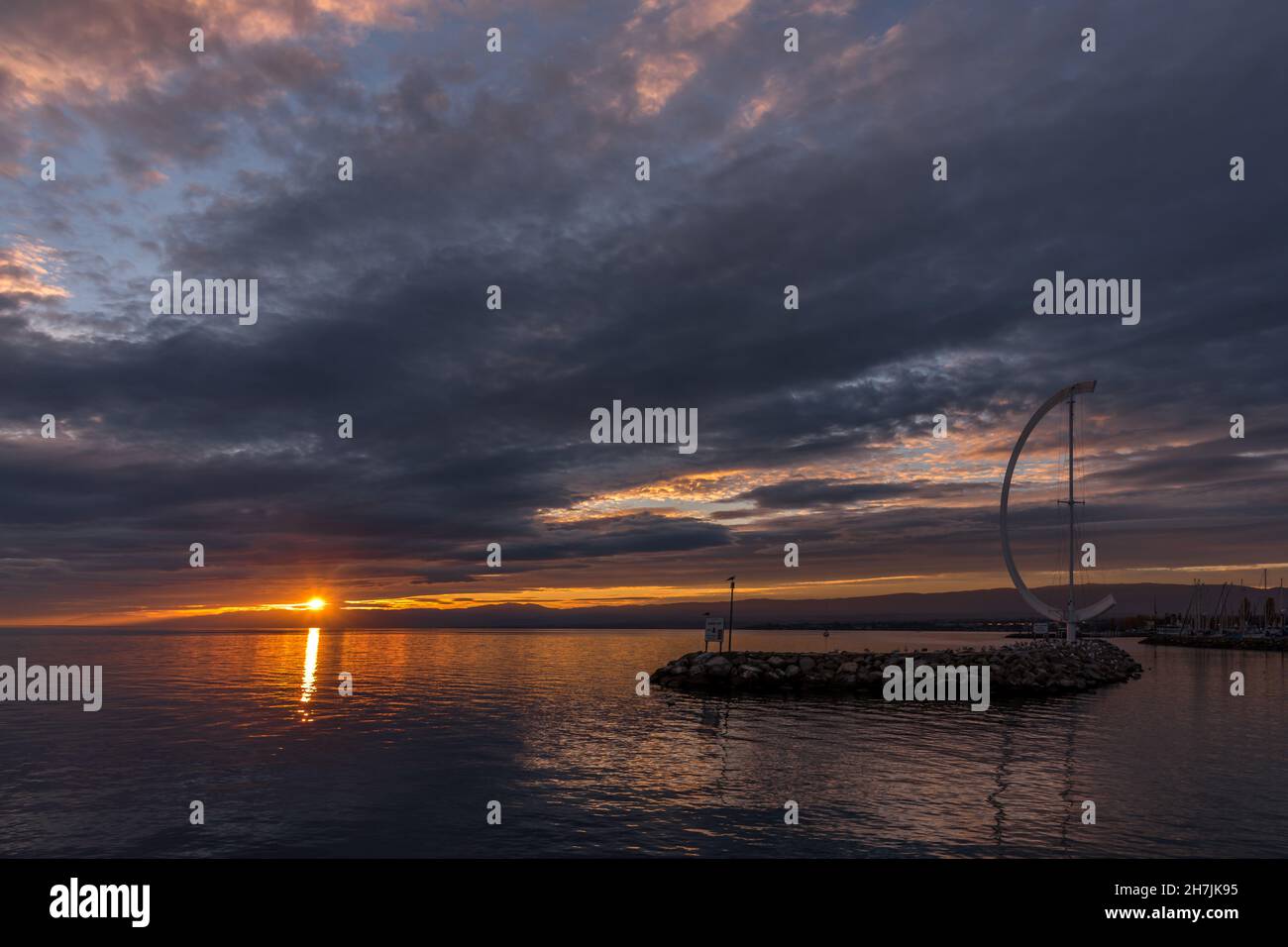 Losanna, Svizzera - 02 novembre 2020: Tramonto a Port d'Ouchy a Losanna. Sole tra le nuvole e indicatore di vento. Foto Stock