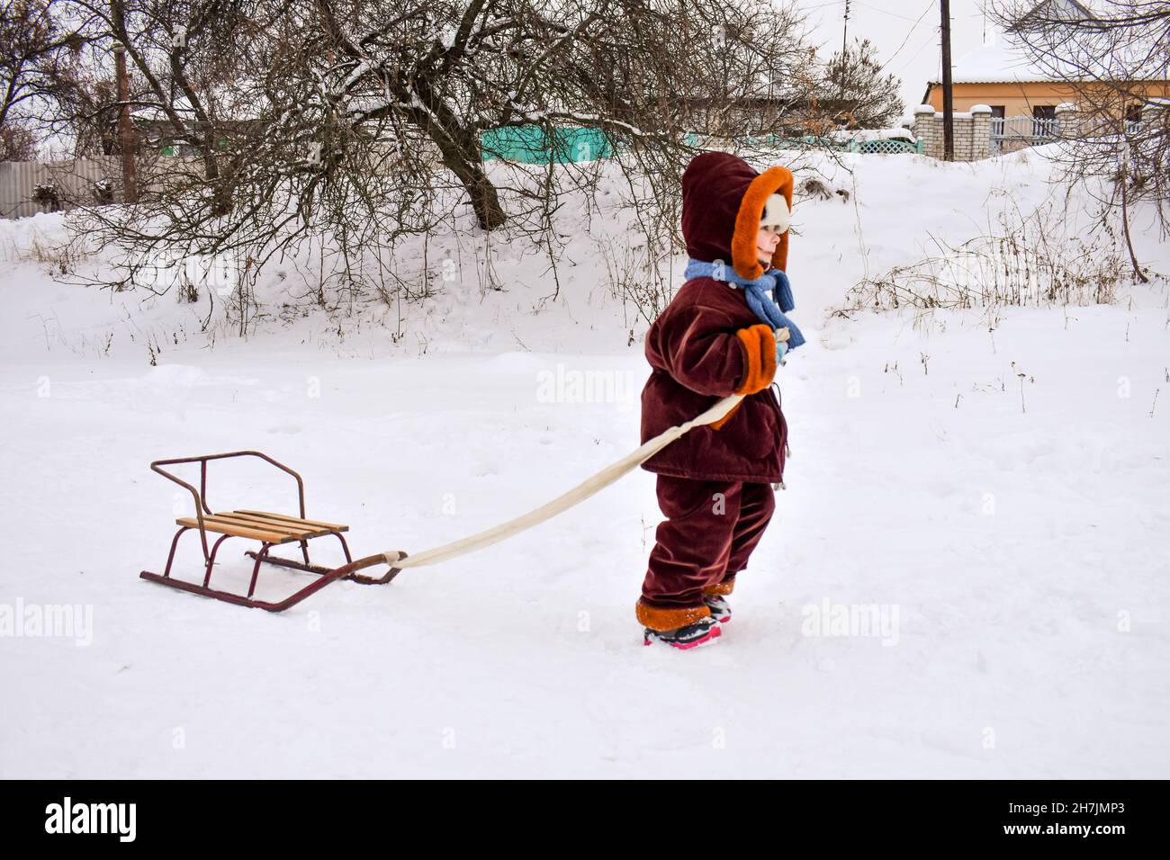 Piccolo bambino che tira una slitta nella neve. Il bambino sta cavalcando su una slitta. I bambini giocano fuori nella neve, i bambini cavalcano. Divertimento all'aperto per tutta la famiglia Foto Stock