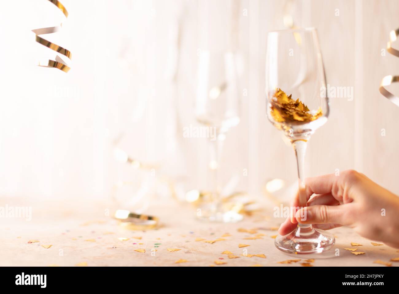 Bicchieri da champagne di Capodanno in mano con scintille all'interno. Su sfondo bianco di tinsel e nastri. Vista frontale. Foto Stock