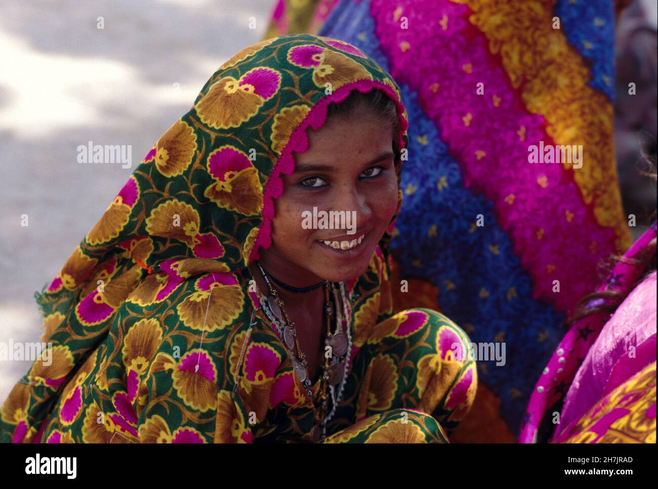 Una donna della Magwartribe siede nel suo colorato costume tradizionale, nel villaggio di Kasbo, nella regione di Nagar Parkar del deserto di Tharparkar, in Pakistan Foto Stock