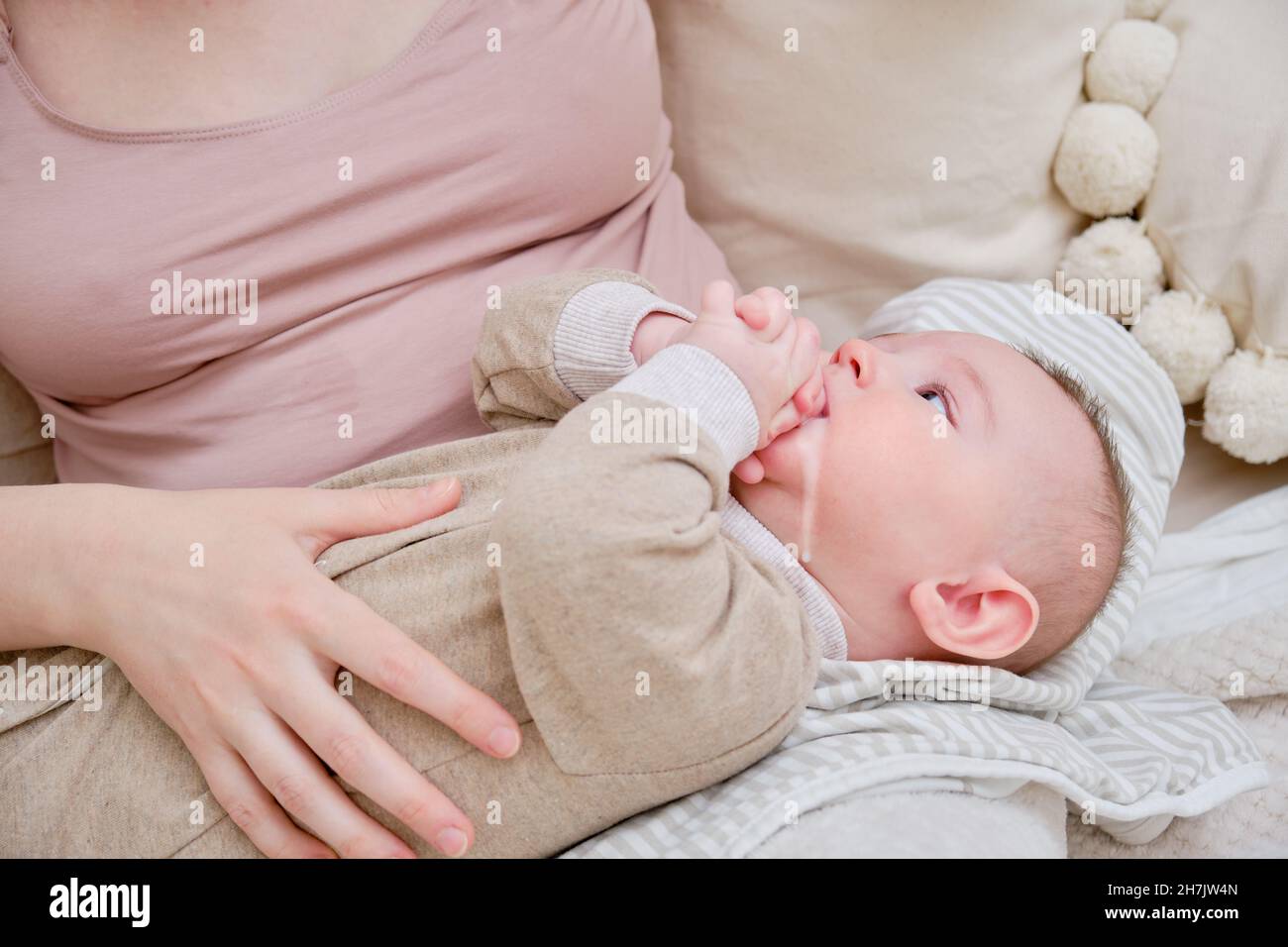 Una donna madre tiene un bambino per rigurgitare l'aria in eccesso dopo l'allattamento al seno. Mamma con un bambino dopo aver nutrito Foto Stock