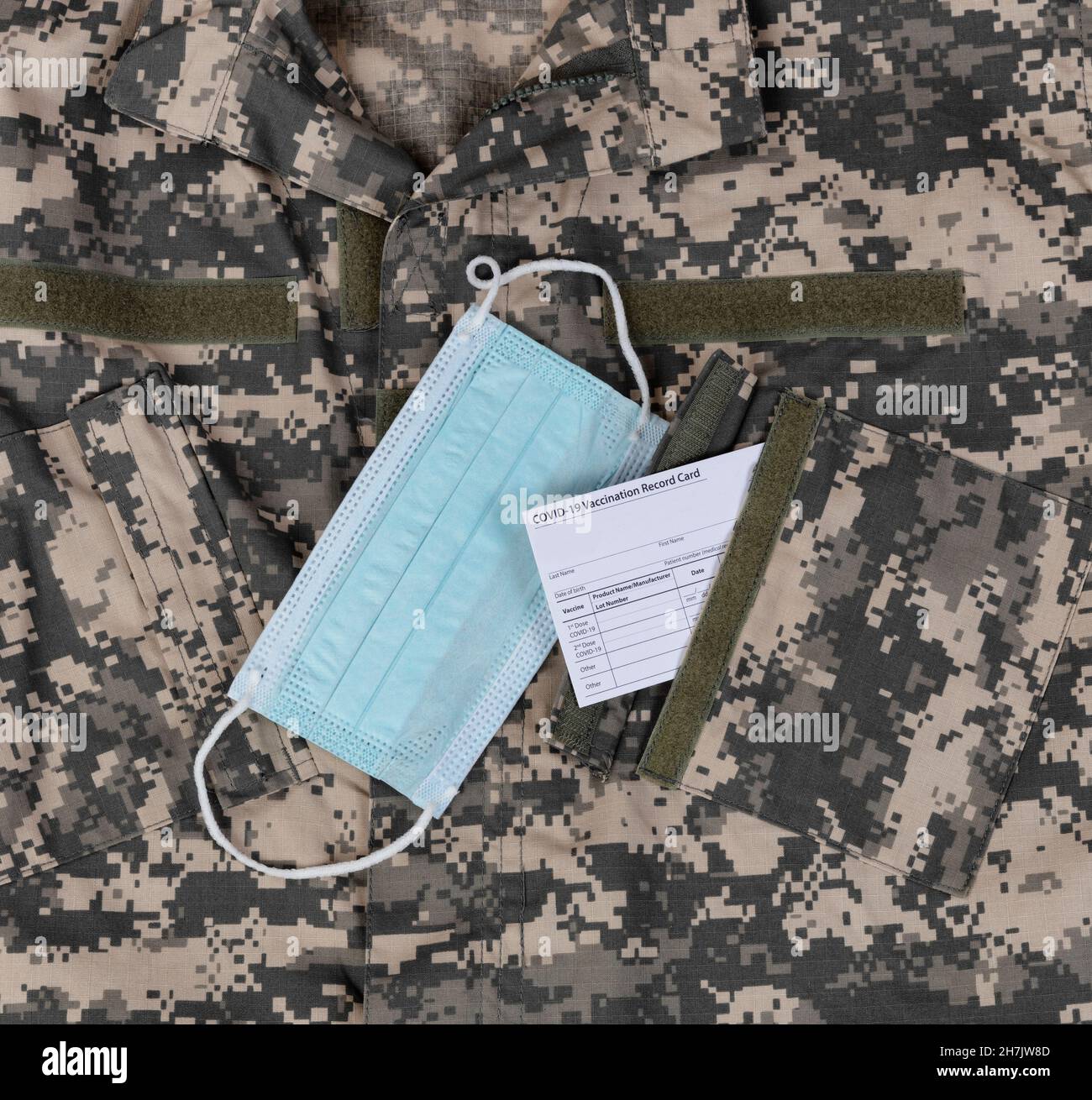 Un top uniforme militare con carta vaccino Covid 19 e maschera facciale personale in tasca Foto Stock