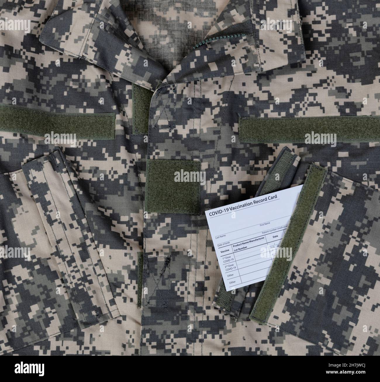 Un top uniforme militare con la carta vaccino Covid 19 in tasca Foto Stock