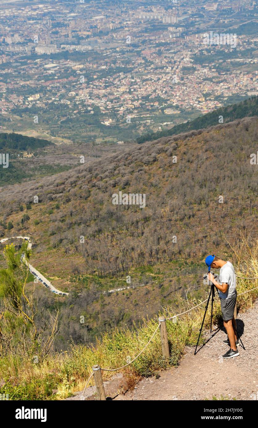 Napoli, Italia - Agosto 2019: Persona che scatta una fotografia con una macchina fotografica utilizzando un cavalletto su un sentiero fino alla cima del Vesuvio Foto Stock