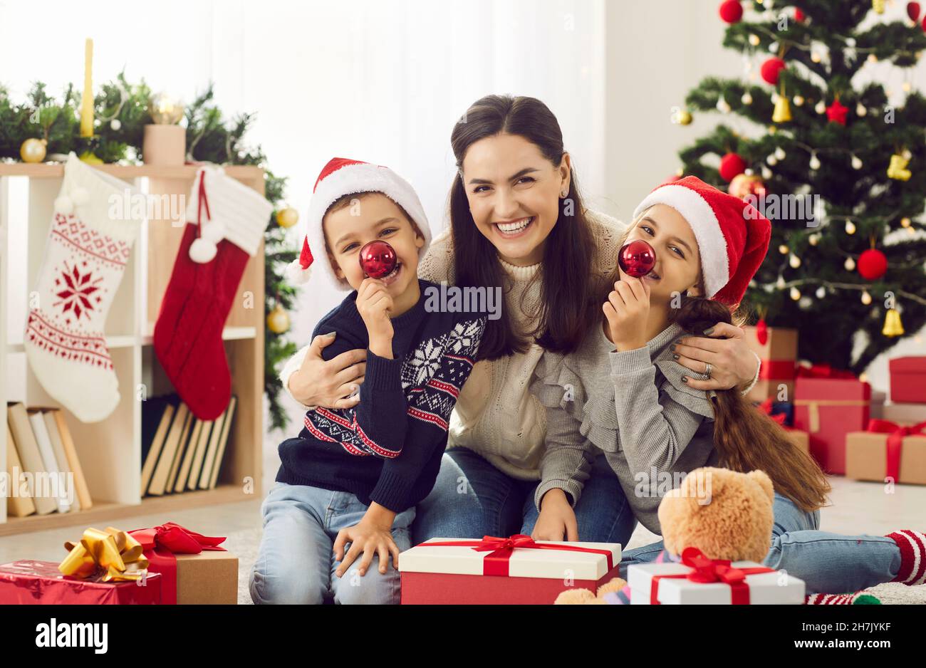 Ritratto divertente di felice, sorridente madre e bambini piccoli il giorno di Natale mattina a casa Foto Stock