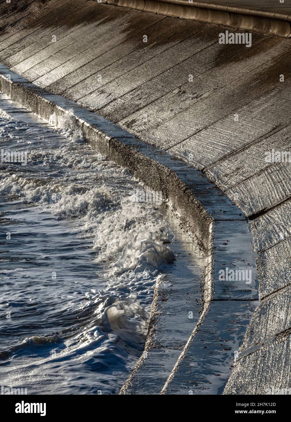 astratto muro di difesa del mare costiero, muro di cemento curvo fronte mare con onde che si infrangono contro il litorale, mare ruvido che batte la costa in tempesta. Foto Stock