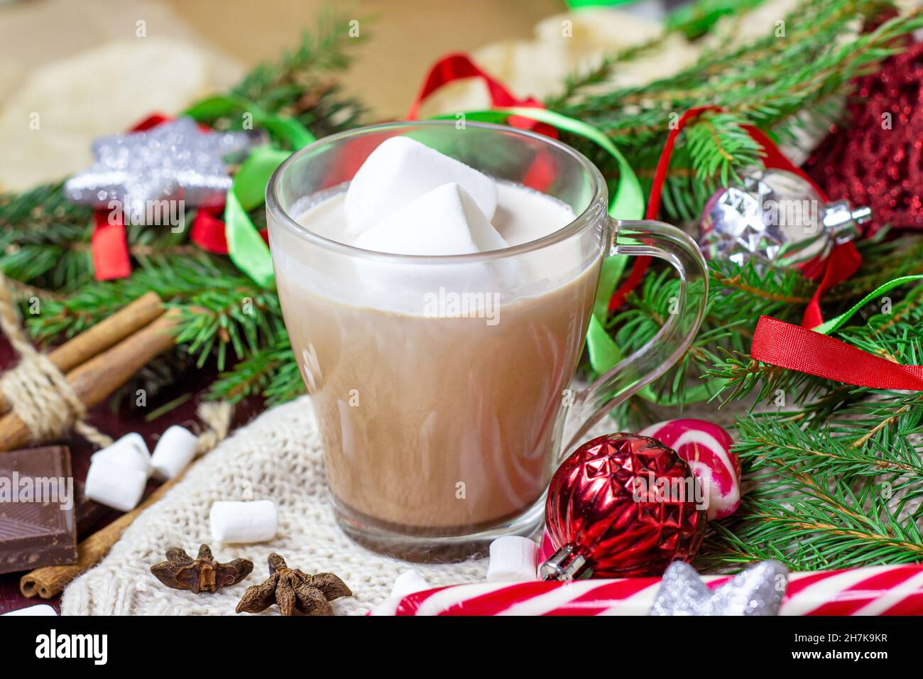 Cioccolata calda Natale e Capodanno celebrazione bevanda di cacao in una tazza di vetro con rami di abete, decorazioni per le vacanze e dolce rosso lollipop a strisce Foto Stock