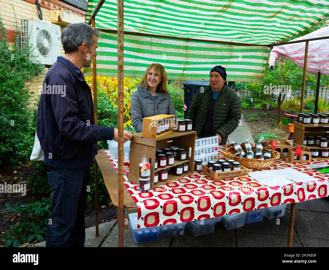 Stallholders con una mostra di marmellata, sottaceti e chutney chiacchierando con un giovane al mercato agricolo mensile a Saltburn North Yorkshire Foto Stock
